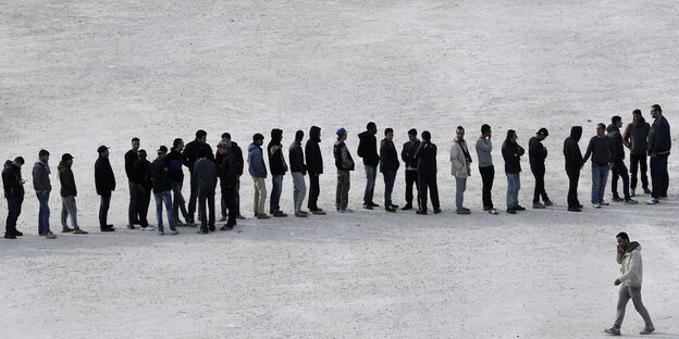 Flüchtlinge stehen in einer langen Schlange Flüchtlinge stehen in einer langen Schlange