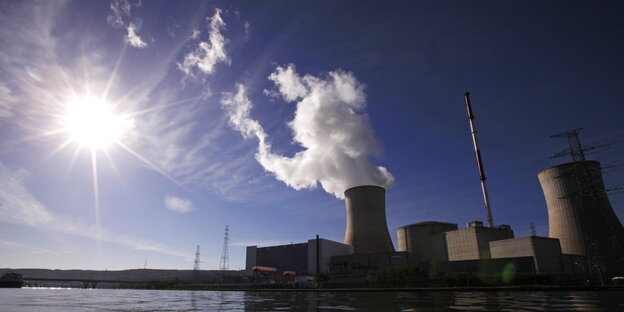 Atomkraftwerk mit dampfendem Kühlturm unter einem blauen Himmel. Atomkraftwerk mit dampfendem Kühlturm unter einem blauen Himmel.