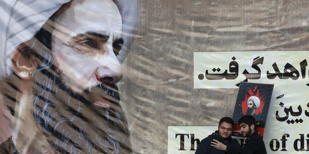 Zwei Männer vor einem Poster von Nimr al-Nimr Zwei Männer vor einem Poster von Nimr al-Nimr