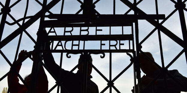 drei Arbeiter montieren „Arbeit mach Frei“ an das KZ-Tor von Dachau drei Arbeiter montieren „Arbeit mach Frei“ an das KZ-Tor von Dachau