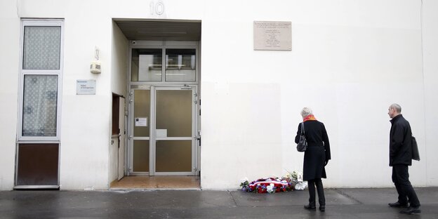 Zwei Menschen stehen vor Blumen vor einem Gebäude Zwei Menschen stehen vor Blumen vor einem Gebäude