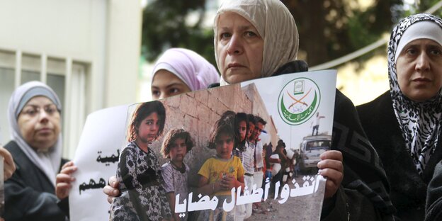 Vier Frauen halten auf einer Demonstration in Beirut ein Schild gegen die Belagerung Madayas hoch, auf dem in arabischer Sprache steht "Rettet Madayas Kinder" Vier Frauen halten auf einer Demonstration in Beirut ein Schild gegen die Belagerung Madayas hoch, auf dem in arabischer Sprache steht "Rettet Madayas Kinder"