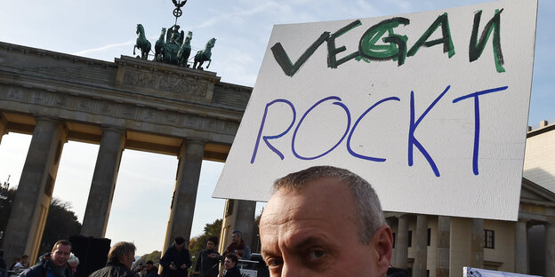 Demonstrant mit Transparent „vegan rockt“ vor dem Brandenburger Tor Demonstrant mit Transparent „vegan rockt“ vor dem Brandenburger Tor