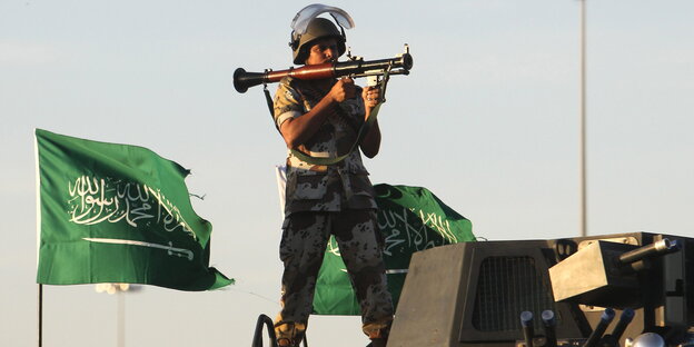 Ein saudischer Soldat steht auf einem Militärfahrzeug, im Hintergrund eine saudische Flagge Ein saudischer Soldat steht auf einem Militärfahrzeug, im Hintergrund eine saudische Flagge