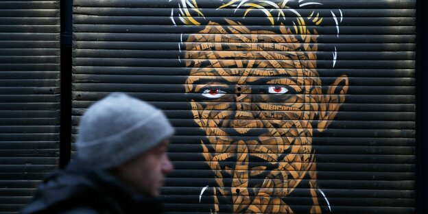 Ein Mann läuft vor einem Portrait von David Bowie Ein Mann läuft vor einem Portrait von David Bowie