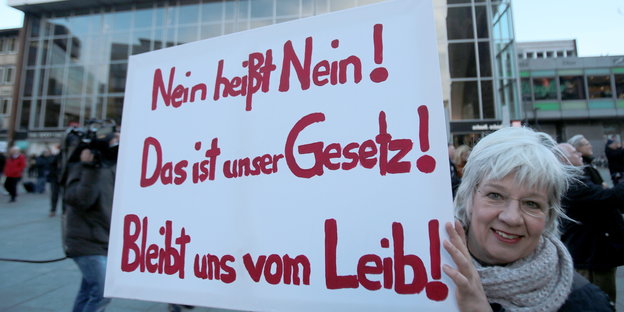 Frau demonstriert mit einem Schild vor dem Kölner Hauptbahnhof. Auf dem Schild steht "Nein heißt Nein!""