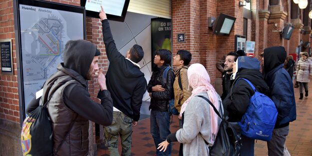 Gruppe von Flüchtlingen schaut auf eine Anzeigetafel im Kopenhagener Bahnhof Gruppe von Flüchtlingen schaut auf eine Anzeigetafel im Kopenhagener Bahnhof