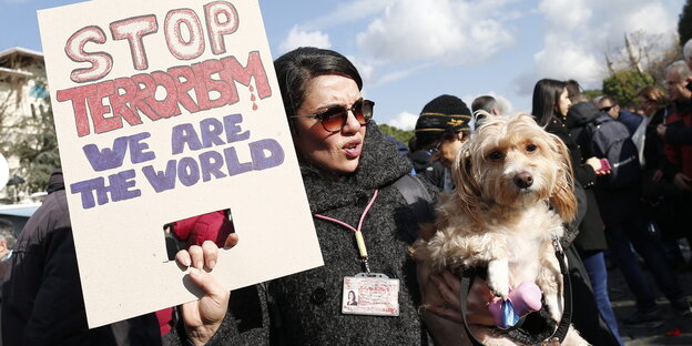 Eine Frau hält ein Schild hoch, auf dem "Stop Terrorism" steht.