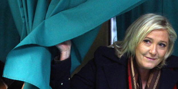 Marine Le Pen schiebt einen Vorhang beiseite Marine Le Pen schiebt einen Vorhang beiseite