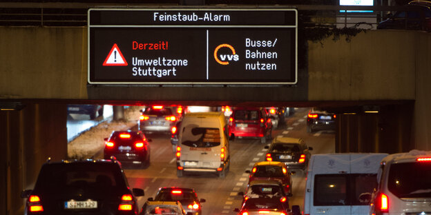 Autos von hinten auf einer Autobahn, darüber digitales Schild, auf dem eine Feinstaub-Warnung zu lesen ist und die Aufforderung, Bus und Bahn zu nutzen Autos von hinten auf einer Autobahn, darüber digitales Schild, auf dem eine Feinstaub-Warnung zu lesen ist und die Aufforderung, Bus und Bahn zu nutzen