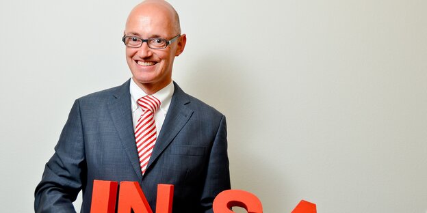 Mann mit Glatze und Brille in einem Anzug mit rot-weiß-gestreifter Krawatte. Mann mit Glatze und Brille in einem Anzug mit rot-weiß-gestreifter Krawatte.