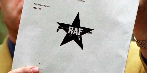 Mensch hält Papier mit RAF-Logo hoch Mensch hält Papier mit RAF-Logo hoch