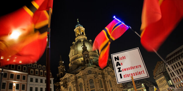 Fahnen wehen vor der Frauenkirche, dazwischen ein Schild mit der Aufschrift "Nazi“ Fahnen wehen vor der Frauenkirche, dazwischen ein Schild mit der Aufschrift "Nazi“