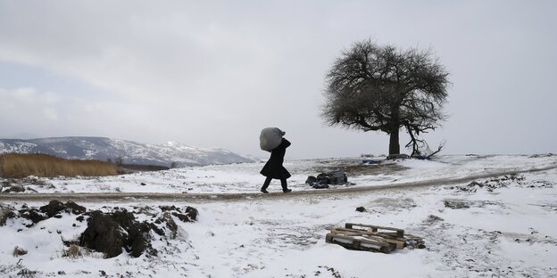 Ein Mann mit einem großen Sack auf den Schultern geht durch eine Winterlandschaft Ein Mann mit einem großen Sack auf den Schultern geht durch eine Winterlandschaft