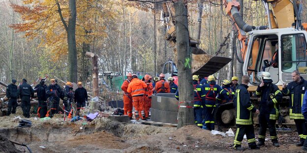 Polizisten und Feuerwehrleute bei einem Bagger im Wald Polizisten und Feuerwehrleute bei einem Bagger im Wald