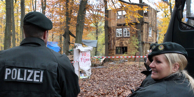 Ein Polizist und eine Polizistin stehen im Hambacher Forst vor einem Holzhäuschen der Besetzer Ein Polizist und eine Polizistin stehen im Hambacher Forst vor einem Holzhäuschen der Besetzer