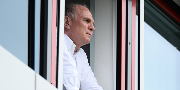 Uli Hoeneß steht an einem geöffneten Fenster und guckt nach draußen