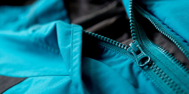 Eine regenabweisende, metallicblaube Jacke in der Nahaufnahme Eine regenabweisende, metallicblaube Jacke in der Nahaufnahme