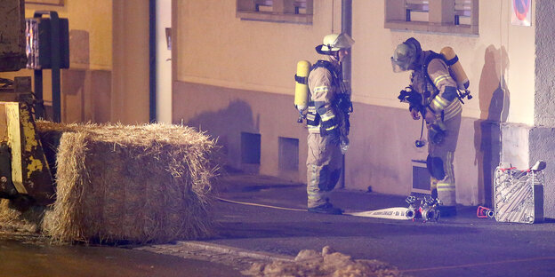 Zwei Feuerwehrmänner vor einem Haus. Zwei Feuerwehrmänner vor einem Haus.