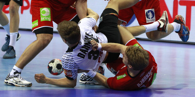 Mehrere Handballer kämpfen um den Ball, einige liegen fast am Boden Mehrere Handballer kämpfen um den Ball, einige liegen fast am Boden