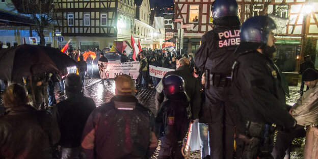 Polizisten stehen vor einer Gruppe Menschen Polizisten stehen vor einer Gruppe Menschen