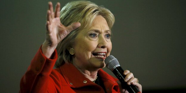 Hillary Clinton spricht in ein Mikrofon und gestikuliert mit der rechten Hand. Hillary Clinton spricht in ein Mikrofon und gestikuliert mit der rechten Hand.