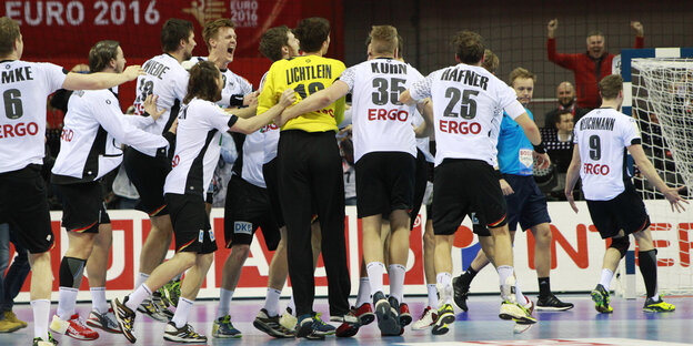 Die Handballer der deutschen Nationalmannschaft stehen auf dem Spielfeld im Kreis und umarmen sich. Die Handballer der deutschen Nationalmannschaft stehen auf dem Spielfeld im Kreis und umarmen sich.