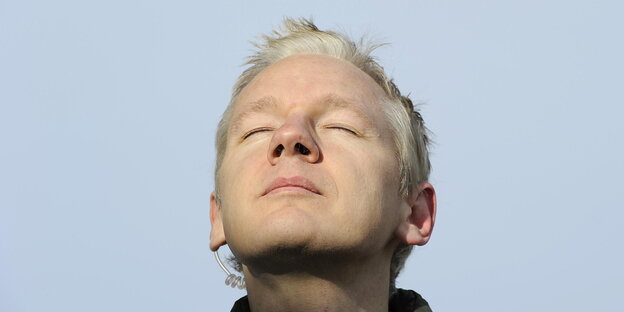 Julian Assange mit geschlossenen Augen vor blauem Himmel Julian Assange mit geschlossenen Augen vor blauem Himmel