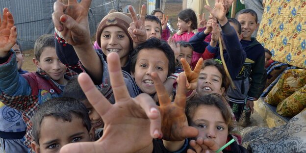 Syrische Flüchtlingskinder lachen und machen das Victory-Zeichen Syrische Flüchtlingskinder lachen und machen das Victory-Zeichen