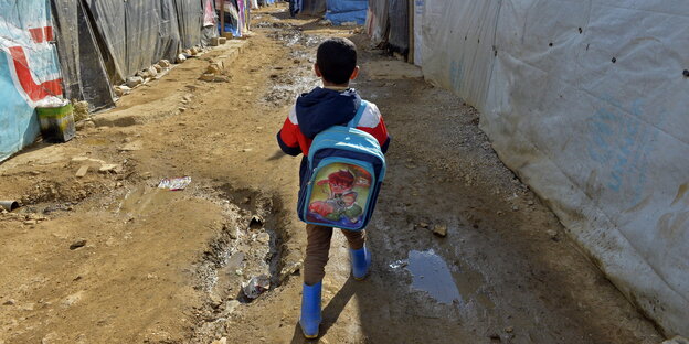 Ein syrischer Junge trägt seinen Rucksack zur Schule Ein syrischer Junge trägt seinen Rucksack zur Schule