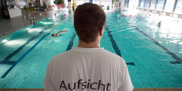 Ein Bademeister beaufsichtigt eine Hallenbadbecken Ein Bademeister beaufsichtigt eine Hallenbadbecken
