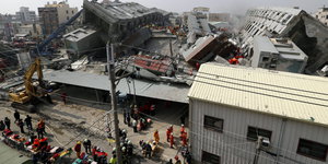 Rettungsautos stehen vor einem eingestürzten Gebäude
