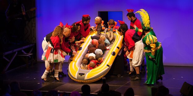 Menschen stehen um ein mit Puppen gefülltes Schlauchboot Menschen stehen um ein mit Puppen gefülltes Schlauchboot