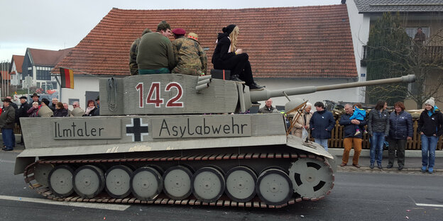 Ein Karnevals-Wagen in Gestalt eines Panzers mit der Aufschrift „Ilmtaler Asylabwehr“ fährt eine Straße entlang Ein Karnevals-Wagen in Gestalt eines Panzers mit der Aufschrift „Ilmtaler Asylabwehr“ fährt eine Straße entlang