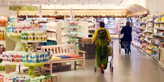 Eine Person schiebt einen Einkaufswagen durch einen Drogeriemarkt. Eine Person schiebt einen Einkaufswagen durch einen Drogeriemarkt.