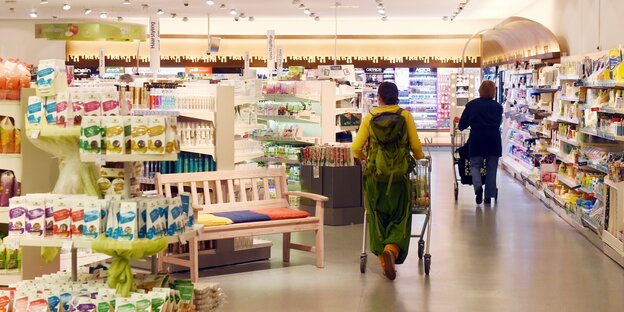 Eine Person schiebt einen Einkaufswagen durch einen Drogeriemarkt.