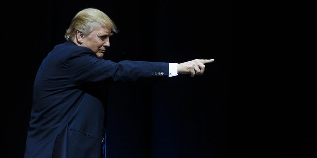 Donald Trump im Profil zeigt vor schwarzem Hintergrund auf seine Unterstützer Donald Trump im Profil zeigt vor schwarzem Hintergrund auf seine Unterstützer