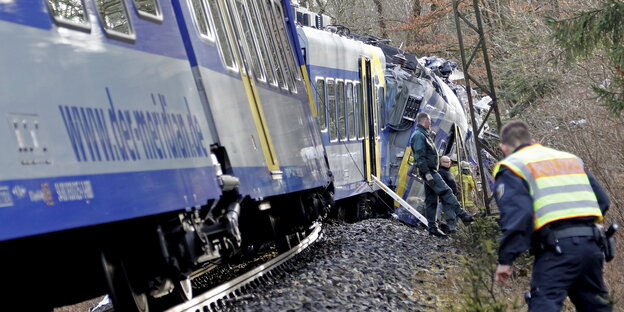 Ein verunfallter Zug in einem Waldstück. Am Gleisbett stehen Rettungskräfte und Polizei. Ein verunfallter Zug in einem Waldstück. Am Gleisbett stehen Rettungskräfte und Polizei.
