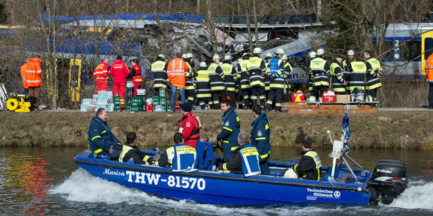 Rettungskräfte sammeln sich an Land und auf einem Boot vor dem verunglückten Zug Rettungskräfte sammeln sich an Land und auf einem Boot vor dem verunglückten Zug