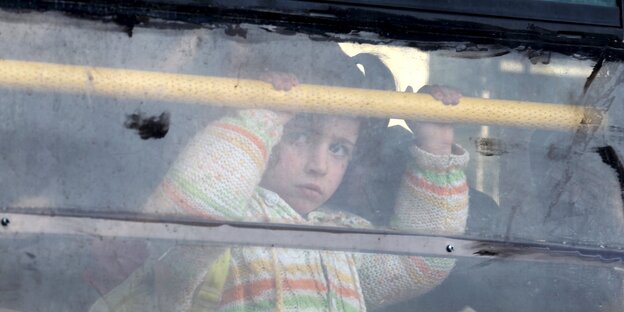Ein junges syrisches Mädchen guckt traurig aus einem Busfenster Ein junges syrisches Mädchen guckt traurig aus einem Busfenster