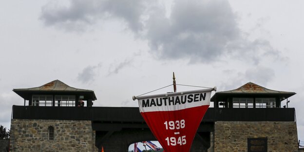 Ein roter Erinnerungswimpel vor dem Eingangstor des ehemaligen Konentrationslagers Mauthausen Ein roter Erinnerungswimpel vor dem Eingangstor des ehemaligen Konentrationslagers Mauthausen