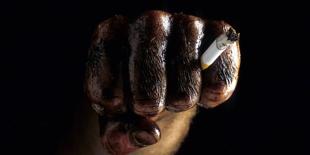 Ölverschmierte Hände mit einer Zigarette in der Hand. Ölverschmierte Hände mit einer Zigarette in der Hand.