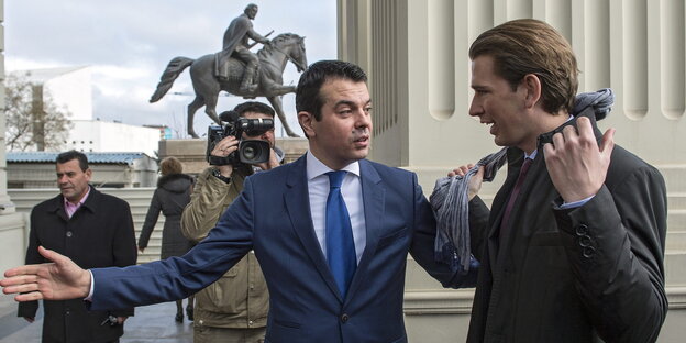 Die zwei Minister im Freien, Popovski gestikuliert, im Hintergrund ein Reiterstandbild. Die zwei Minister im Freien, Popovski gestikuliert, im Hintergrund ein Reiterstandbild.