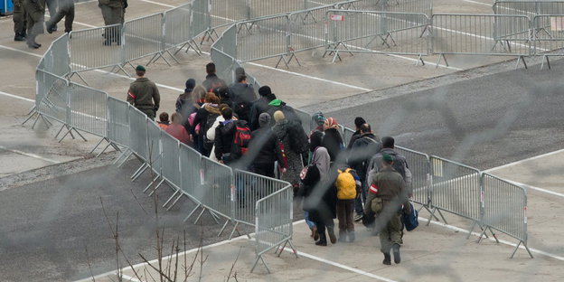 Menschen laufen durch ein Gelände voller Zäune