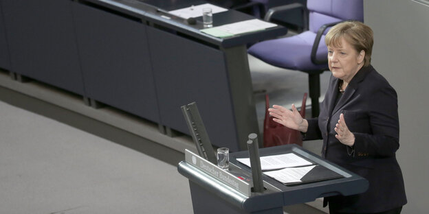 Angela Merkel steht mit erhobenen Händen vor einem Rednerinnenpult Angela Merkel steht mit erhobenen Händen vor einem Rednerinnenpult