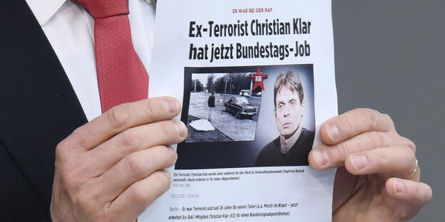 zwei Hände halten ein Blatt Papier, auf dem steht „Ex-Terrorist Christian Klar hat jetzt Bundestagsjob“ zwei Hände halten ein Blatt Papier, auf dem steht „Ex-Terrorist Christian Klar hat jetzt Bundestagsjob“