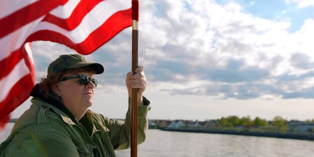 Ein Mann steht an einem Fluss und hält eine amerikanische Flagge. Ein Mann steht an einem Fluss und hält eine amerikanische Flagge.