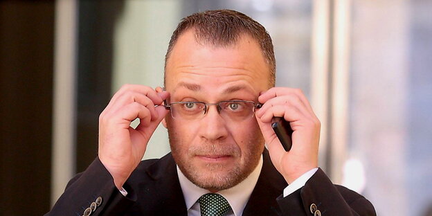 ein Mann fasst sich mit beiden Händen an die Brille ein Mann fasst sich mit beiden Händen an die Brille