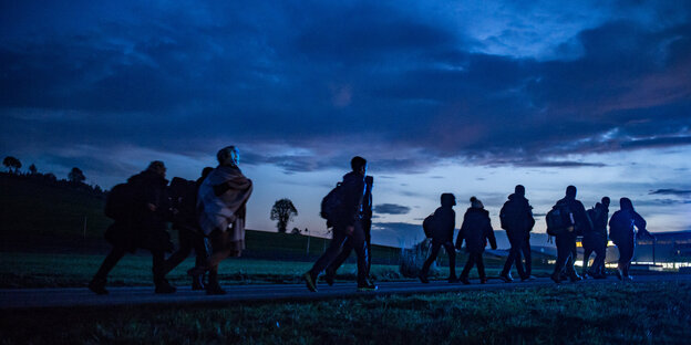 Flüchtlinge gehen in der Dämmerung zu einer Aufnahmestelle Flüchtlinge gehen in der Dämmerung zu einer Aufnahmestelle