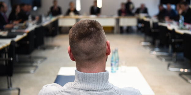 Der Hinterkopf eines Mannes, im Hintergrund Menschen an Tischen Der Hinterkopf eines Mannes, im Hintergrund Menschen an Tischen